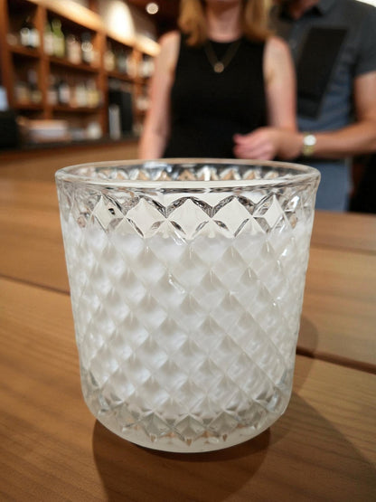 Vela artesanal de doble pabilo elaborada con 340 gramos de cera de soja pura, presentada en elegante vaso de cristal con tapa. La cera de soja garantiza una combustión limpia y prolongada, liberando fragancias de manera uniforme.